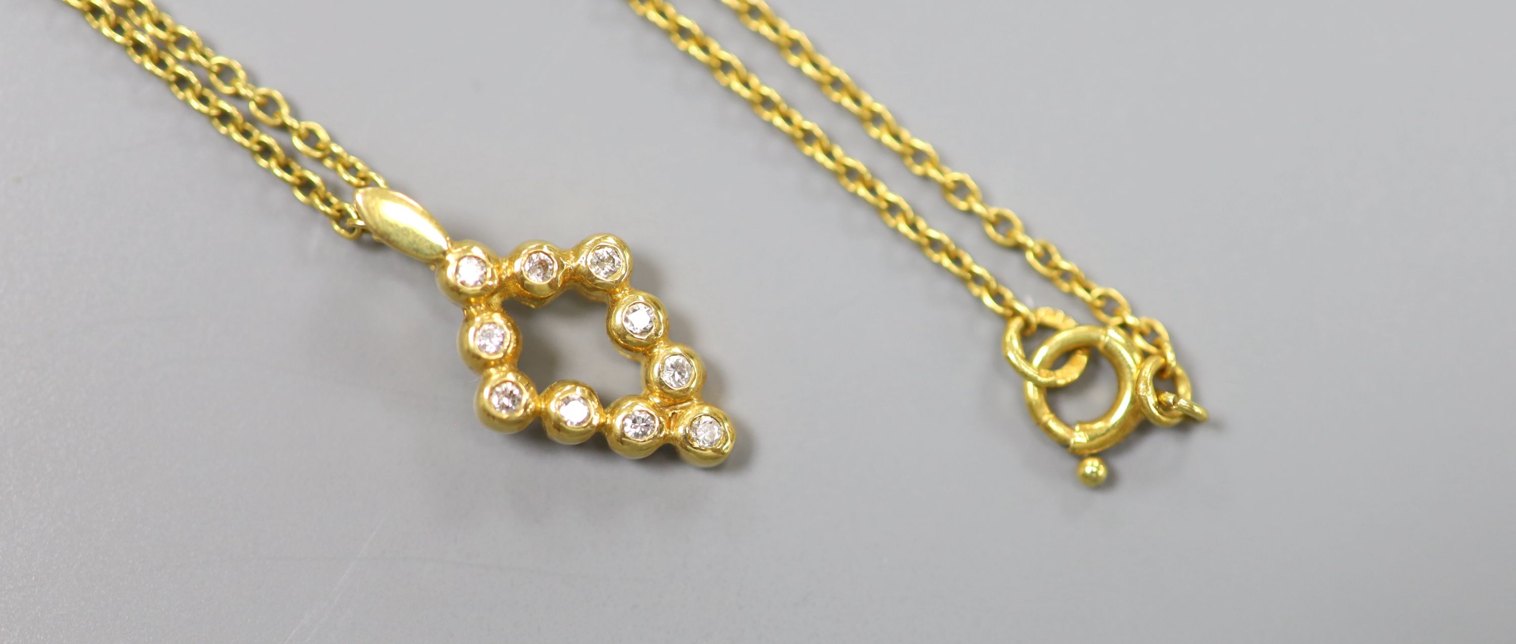 A modern 18ct gold and ten stone diamond chip set pendant, 16mm, on an 18ct chain, 37cm